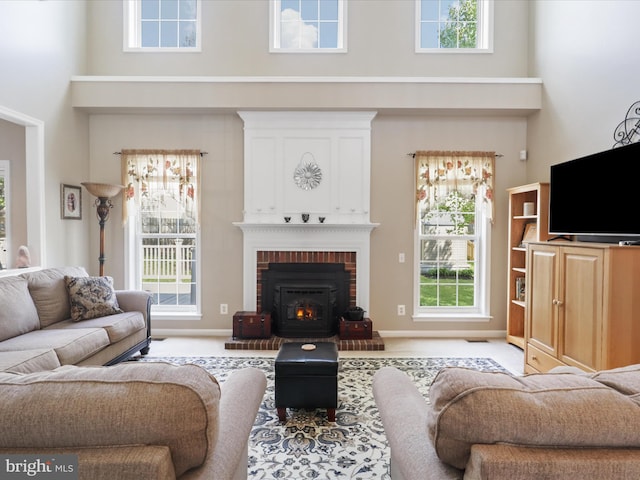 living room featuring a high ceiling, light colored carpet, a brick fireplace, and a wealth of natural light