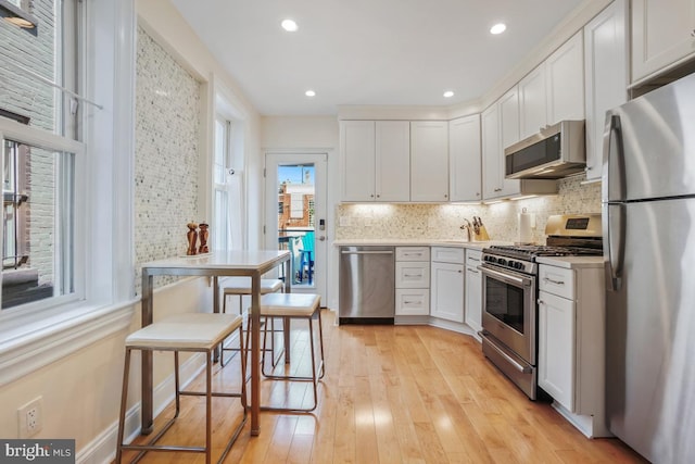 1809 12th St NW, Washington, DC 20009 - kitchen with stainless steel appliances, light wood-style flooring, backsplash, white cabinets, and light countertops