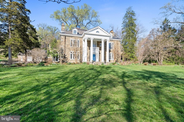 greek revival house with a front yard and a chimney