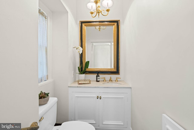 half bathroom featuring vanity, an inviting chandelier, and toilet