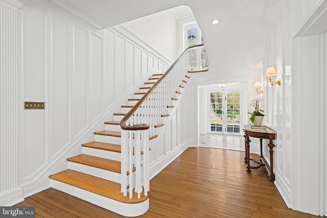 staircase featuring recessed lighting, a decorative wall, hardwood / wood-style flooring, and crown molding