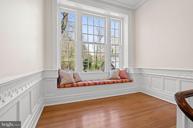 unfurnished room with light wood-style flooring, crown molding, and a wainscoted wall
