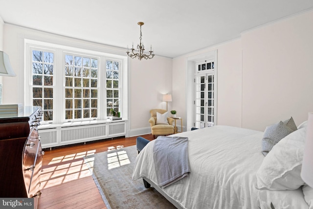 bedroom with hardwood / wood-style floors, radiator heating unit, and an inviting chandelier