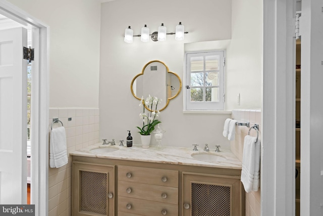 bathroom with double vanity, a sink, and tile walls