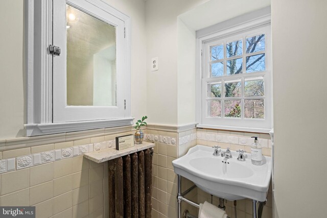 half bath featuring wainscoting, tile walls, and a sink