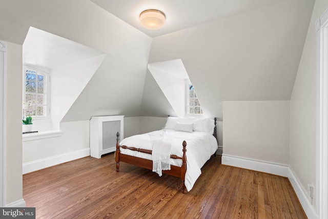 bedroom featuring multiple windows, baseboards, and wood finished floors