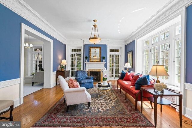 living area featuring ornamental molding, wood-type flooring, an inviting chandelier, and a fireplace