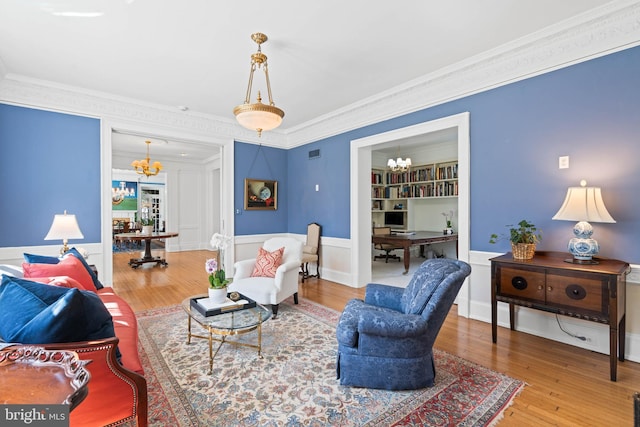 living room with crown molding, wood finished floors, and an inviting chandelier