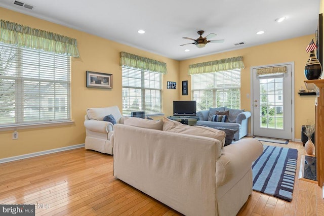 living area featuring light wood-type flooring, ceiling fan, baseboards, and visible vents