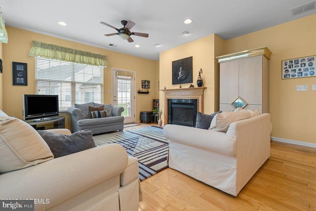 living area featuring light wood-style floors, a fireplace, a ceiling fan, visible vents, and recessed lighting