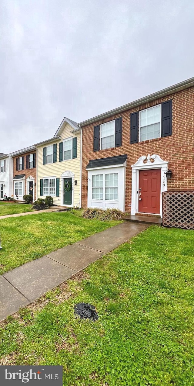 multi unit property featuring a front yard and brick siding