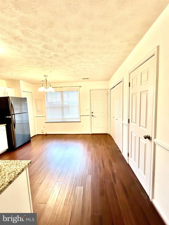 interior space featuring dark wood finished floors, a notable chandelier, and a textured ceiling