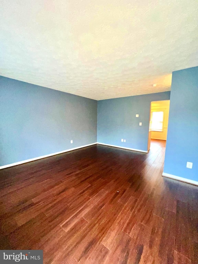 empty room featuring baseboards, a textured ceiling, and wood finished floors