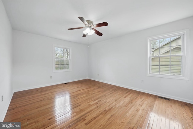 spare room featuring light wood-style floors, baseboards, visible vents, and a ceiling fan