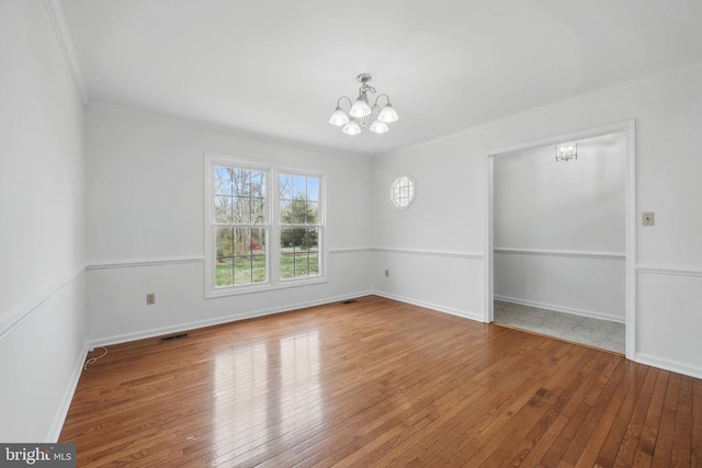 unfurnished dining area featuring wood-type flooring, a notable chandelier, visible vents, and crown molding