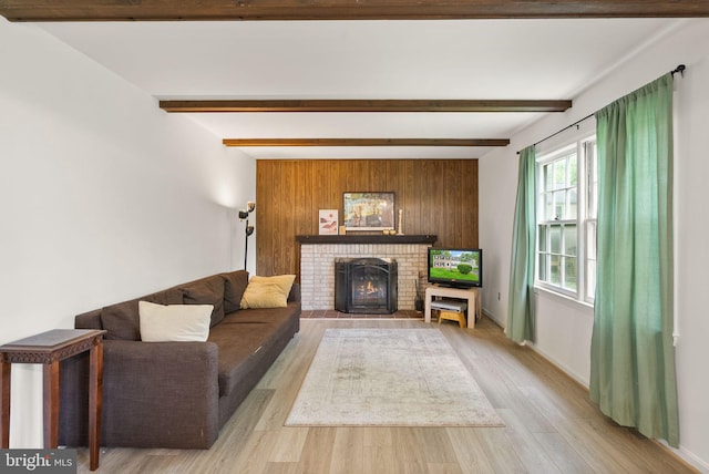 living room featuring wood finished floors, a fireplace, beamed ceiling, wooden walls, and baseboards