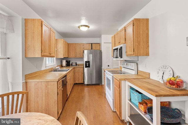 kitchen featuring appliances with stainless steel finishes, light wood-type flooring, a sink, and wood counters