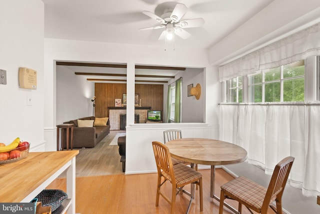 dining area with ceiling fan, light wood-type flooring, and a brick fireplace