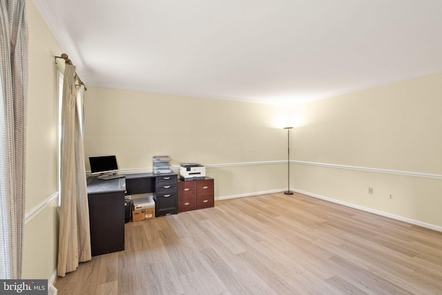 unfurnished office with light wood finished floors, ornamental molding, and baseboards