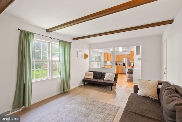 living room with beamed ceiling, light wood-type flooring, and baseboards