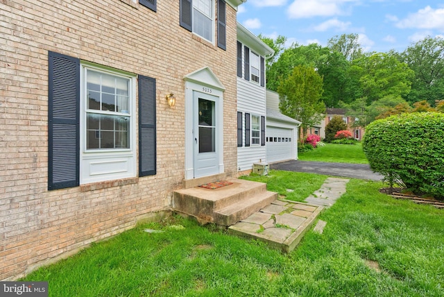 entrance to property with a lawn, a garage, and brick siding