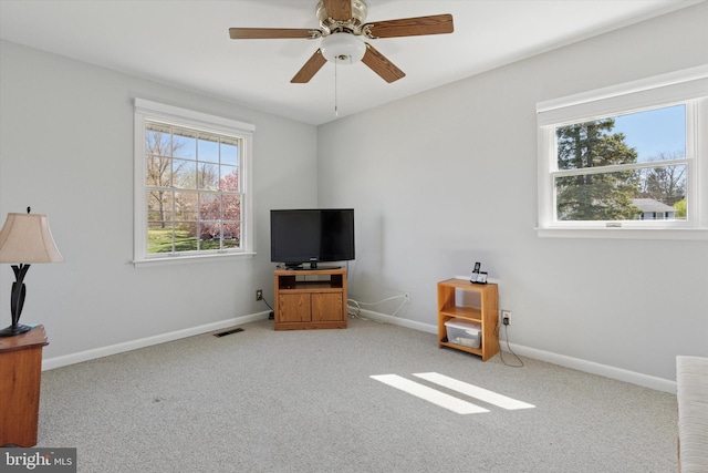 interior space with ceiling fan, carpet flooring, baseboards, and visible vents