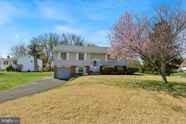 split foyer home featuring driveway, a garage, a front lawn, and brick siding
