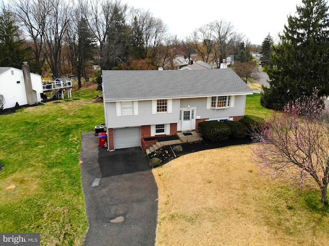 bi-level home with driveway, a front yard, brick siding, a garage, and a shingled roof