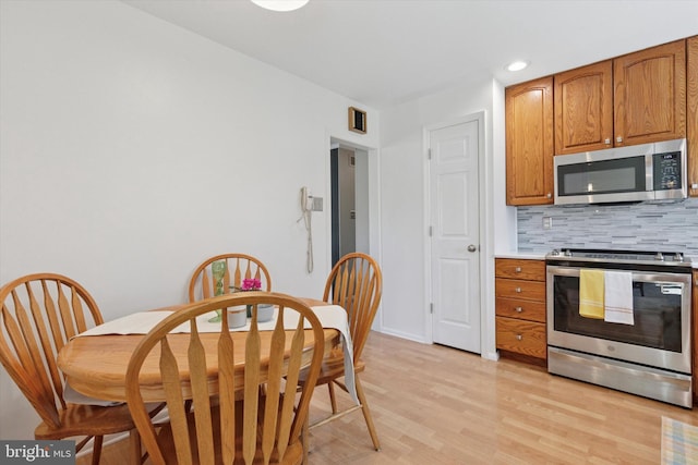 kitchen with tasteful backsplash, light wood-type flooring, visible vents, stainless steel appliances, and brown cabinets