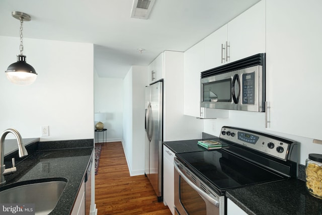 kitchen featuring hanging light fixtures, white cabinets, a sink, dark wood-style flooring, and appliances with stainless steel finishes