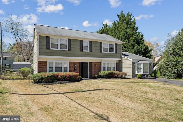 colonial inspired home featuring brick siding and a front yard
