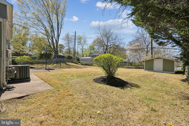 view of yard featuring an outdoor structure, fence, central AC unit, and a storage shed
