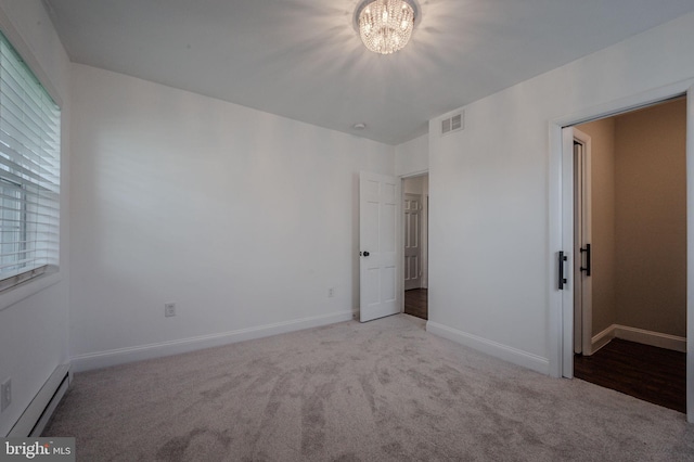 carpeted empty room with baseboards, visible vents, a baseboard radiator, and an inviting chandelier