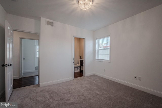 unfurnished bedroom featuring a chandelier, carpet flooring, baseboards, and visible vents