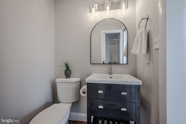 half bath with vanity, baseboards, and toilet