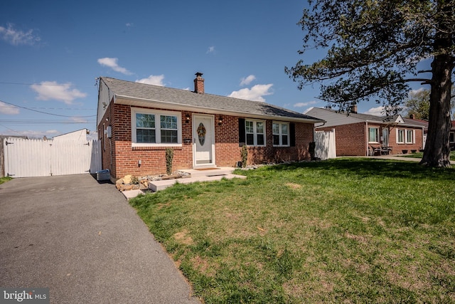 view of front of house with brick siding, a front yard, a gate, and aphalt driveway