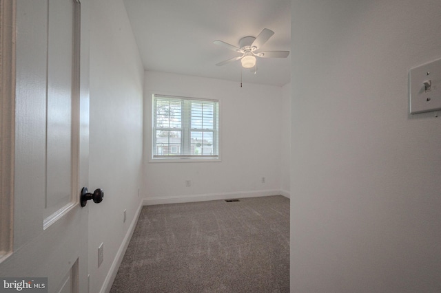 carpeted spare room featuring baseboards and a ceiling fan