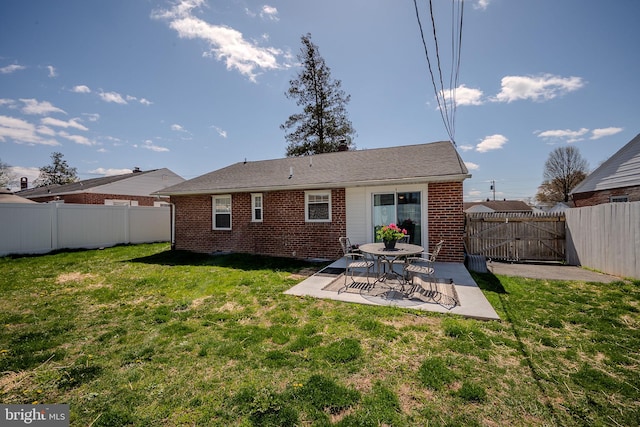 back of house featuring a yard, brick siding, a fenced backyard, and a patio
