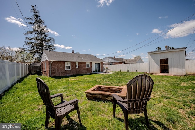 view of yard with a fenced backyard, an outdoor structure, and a fire pit