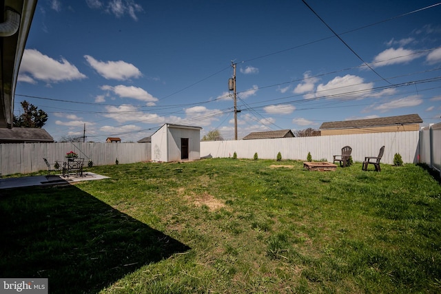 view of yard featuring a shed, a fenced backyard, and an outbuilding