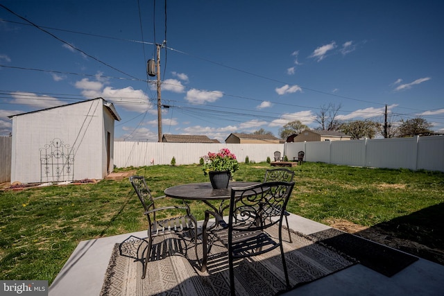 view of patio with an outbuilding, a fenced backyard, a storage shed, and outdoor dining area