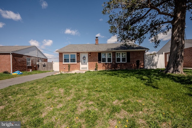 ranch-style house featuring entry steps, fence, a front lawn, brick siding, and a chimney