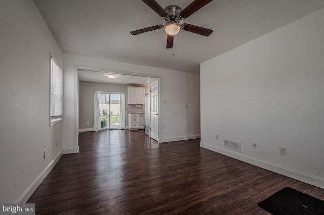 unfurnished living room featuring visible vents, baseboards, a ceiling fan, and dark wood-style floors