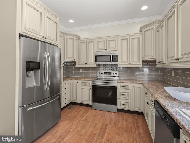 13 N Allegany St, Cumberland, MD 21502 - kitchen with stainless steel appliances, cream cabinets, ornamental molding, decorative backsplash, and light wood finished floors