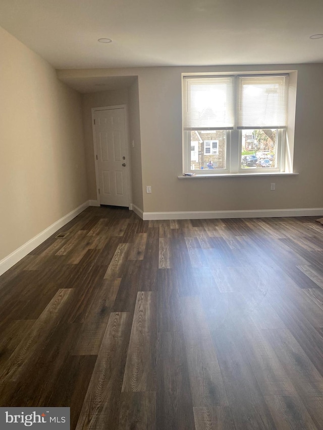 unfurnished room with dark wood-style flooring and baseboards
