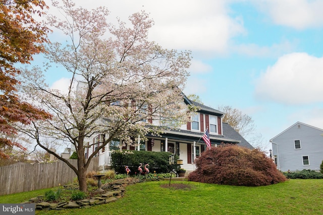 traditional home with fence, a porch, and a front yard
