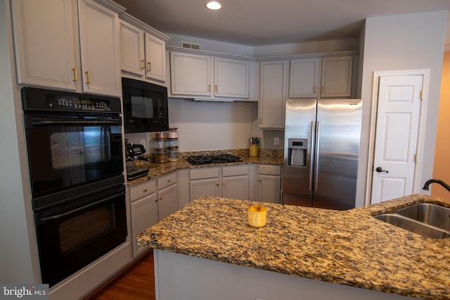 12253 Tulane Falls Dr, Bristow, VA 20136 - kitchen featuring light stone counters, a sink, black appliances, dark wood-style flooring, and recessed lighting