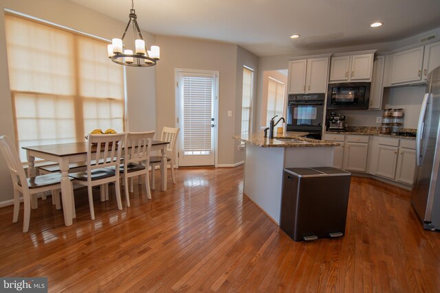 12253 Tulane Falls Dr, Bristow, VA 20136 - kitchen with a sink, freestanding refrigerator, a notable chandelier, black microwave, and wood-type flooring