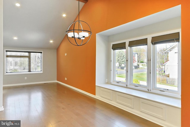 unfurnished dining area featuring baseboards, vaulted ceiling, a chandelier, recessed lighting, and wood finished floors