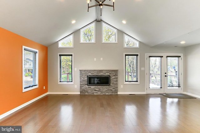 unfurnished living room with a stone fireplace, baseboards, high vaulted ceiling, and wood finished floors